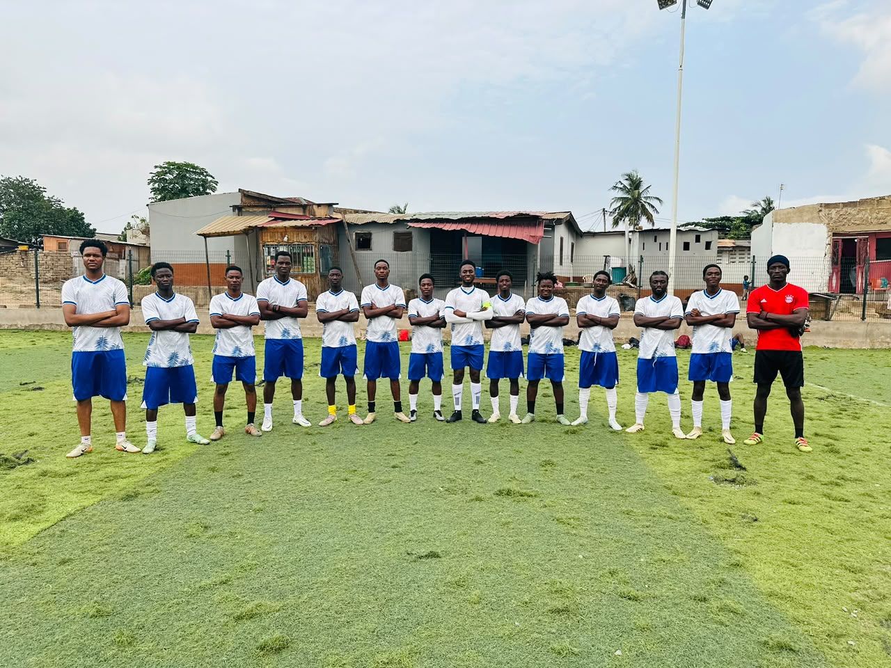 A team of young players in white and blue kit lined up on the pitch