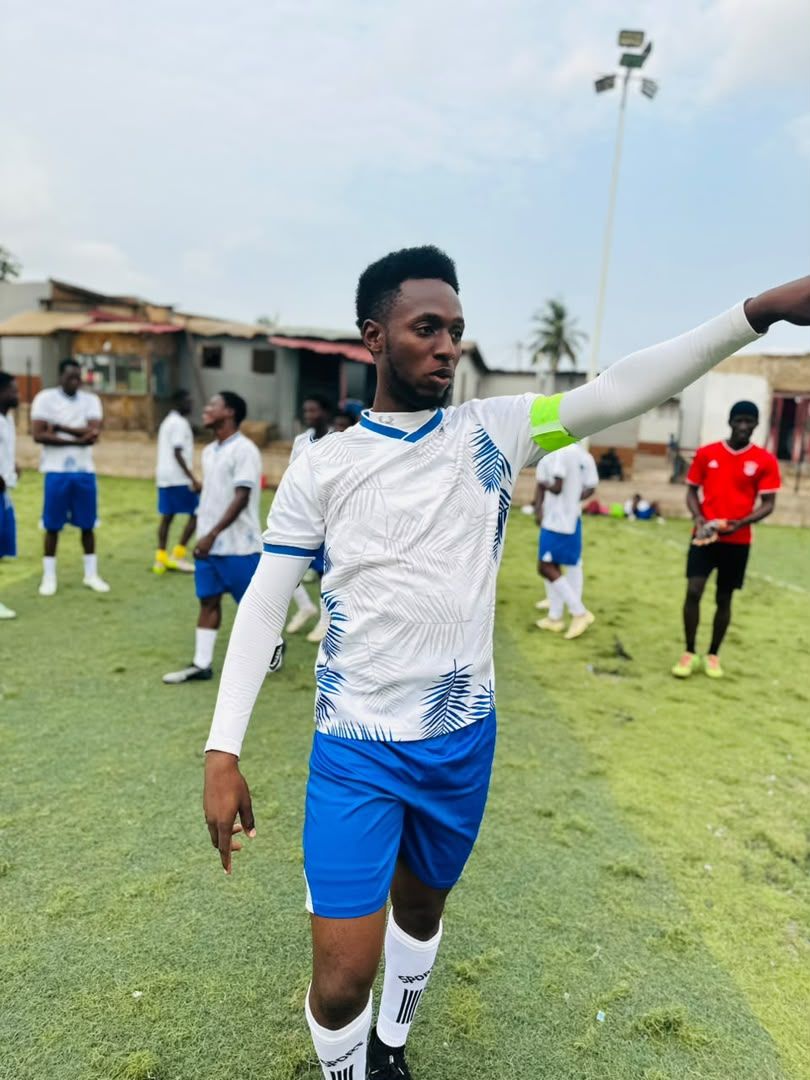 A player in white and blue kit on the pitch, arm raised
